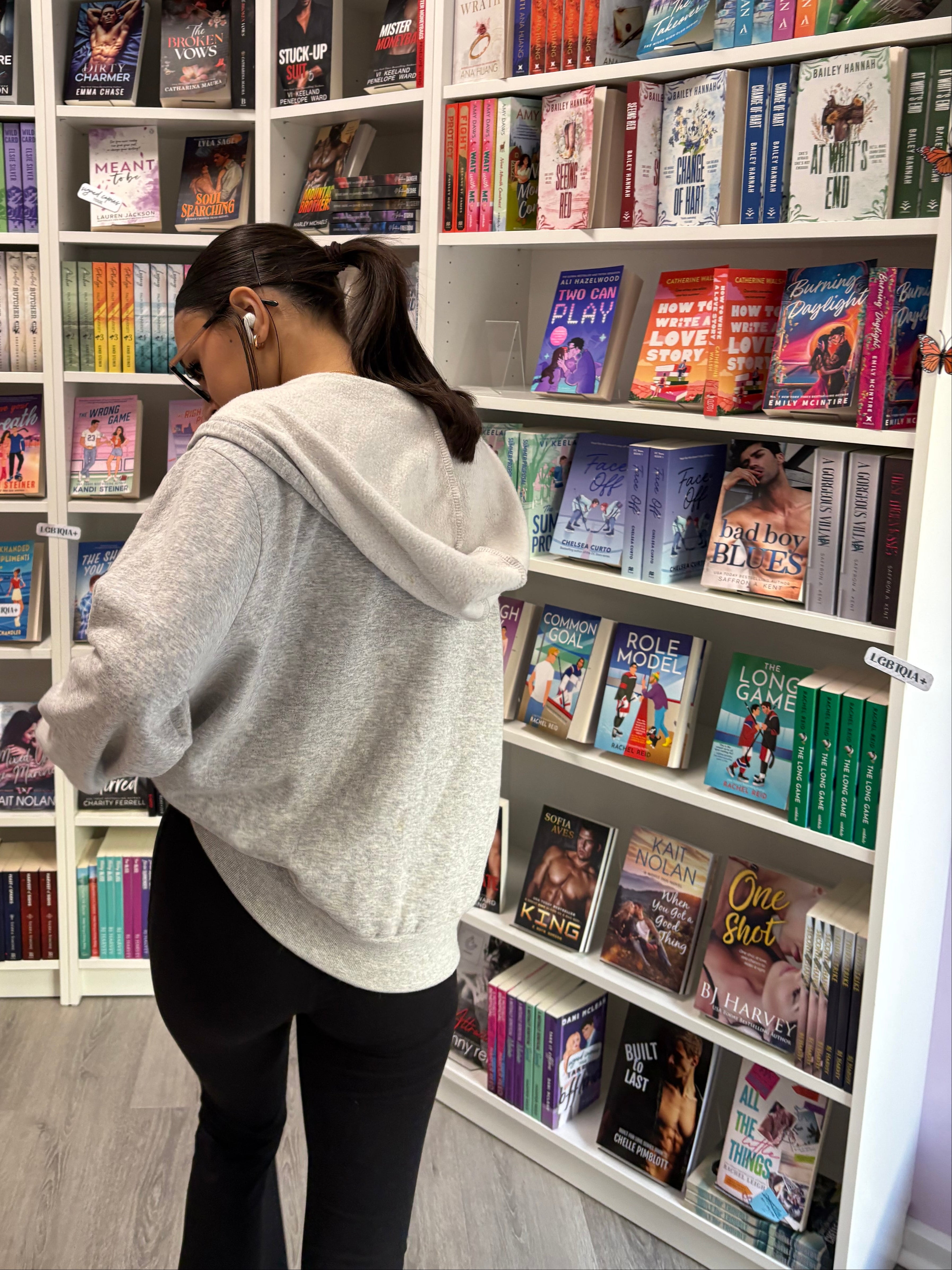 Person browsing books in a bookstore with shelves filled with various titles.